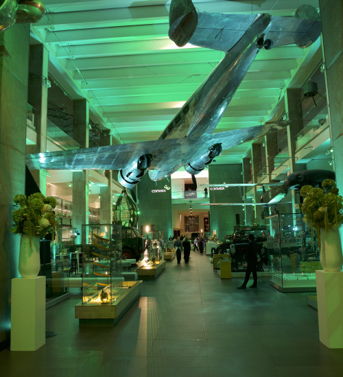 An interior large room with an old airplane in a museum, the room is lit with green ligths.